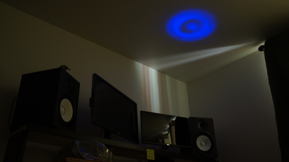 A dark room with a bright blue light beam shining on the ceiling